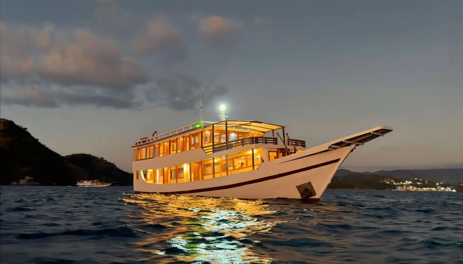Ayvara Cruise lit up at anchor at dusk
