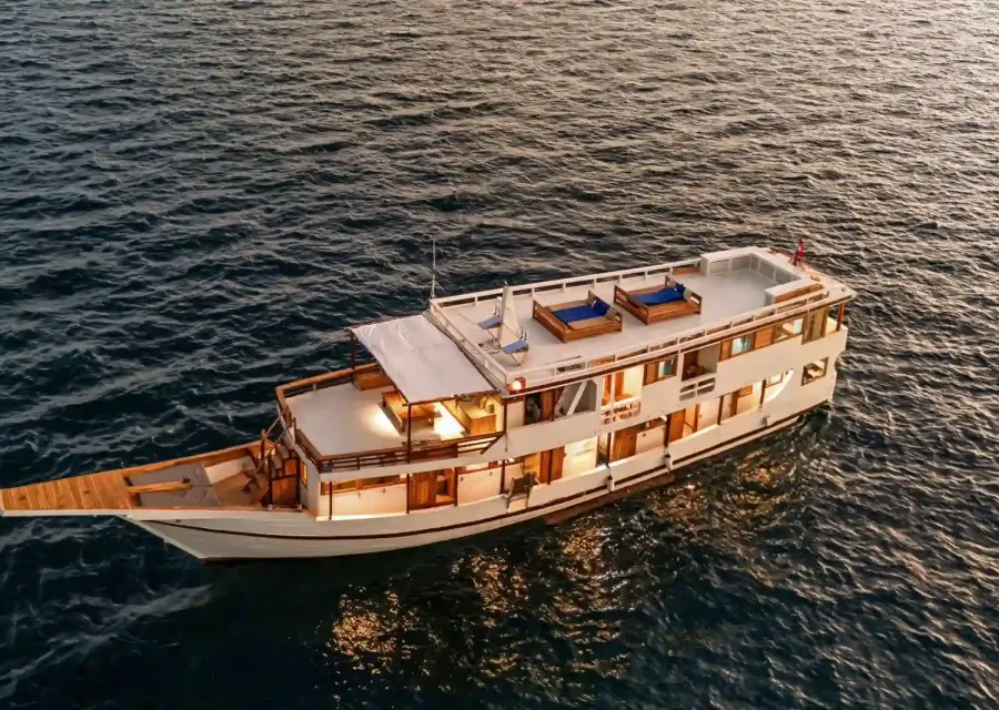 Ayvara Cruise, a white-hulled wooden phinisi, under way at golden hour